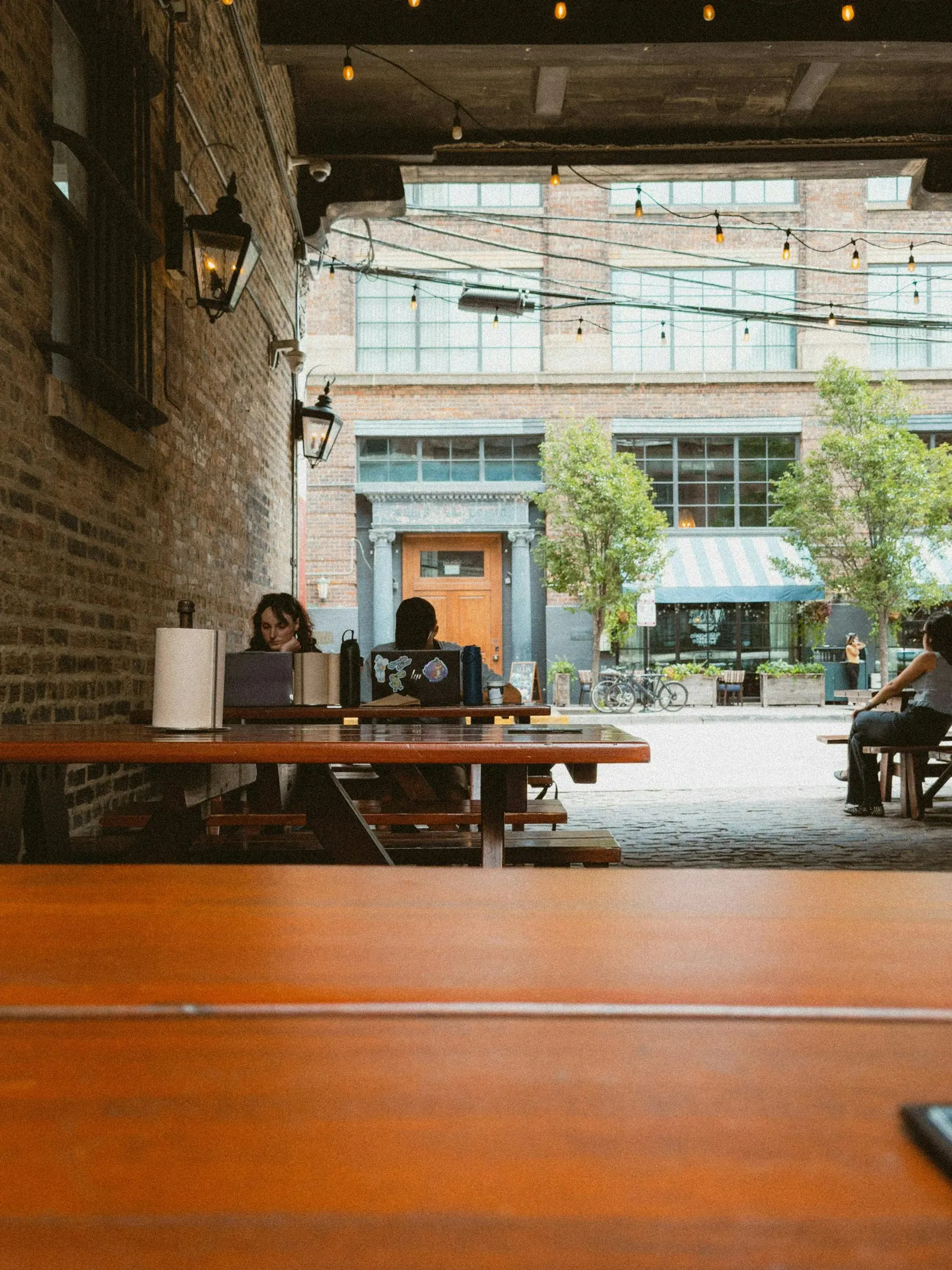 People working with laptops around an outdoor table in a courtyard setting.
