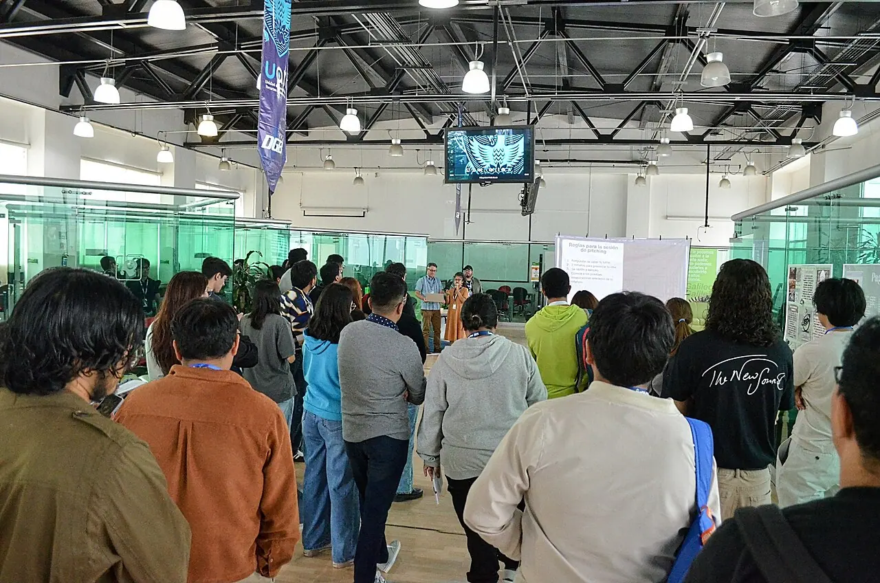 Hackathon participants gathered around a demo session in a bright event space.